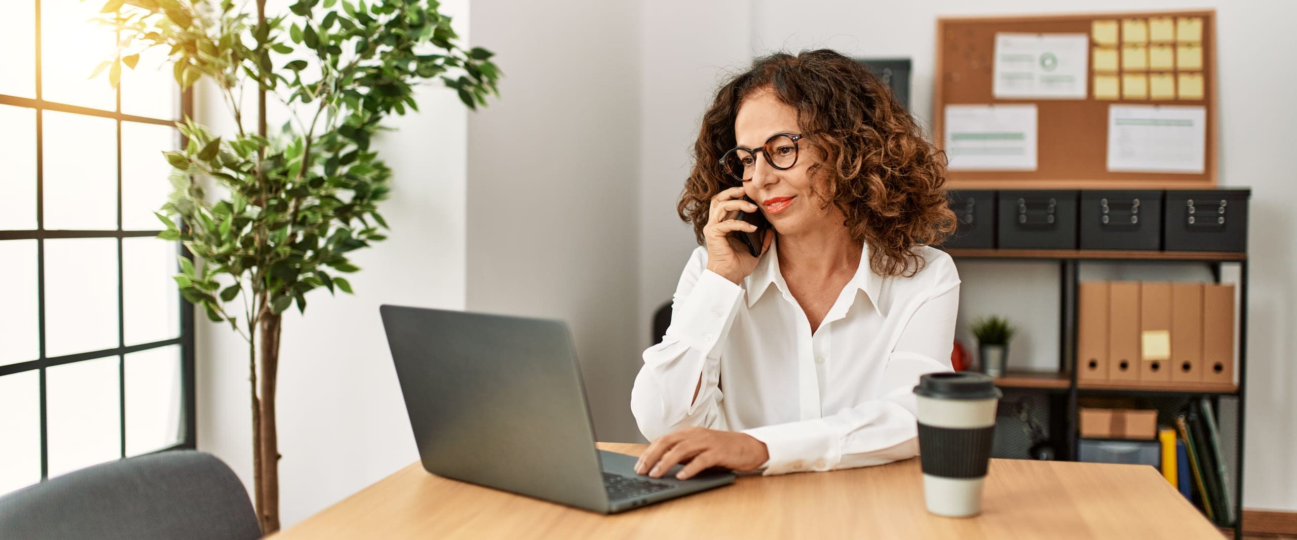 Woman on the phone at her desk with a laptop