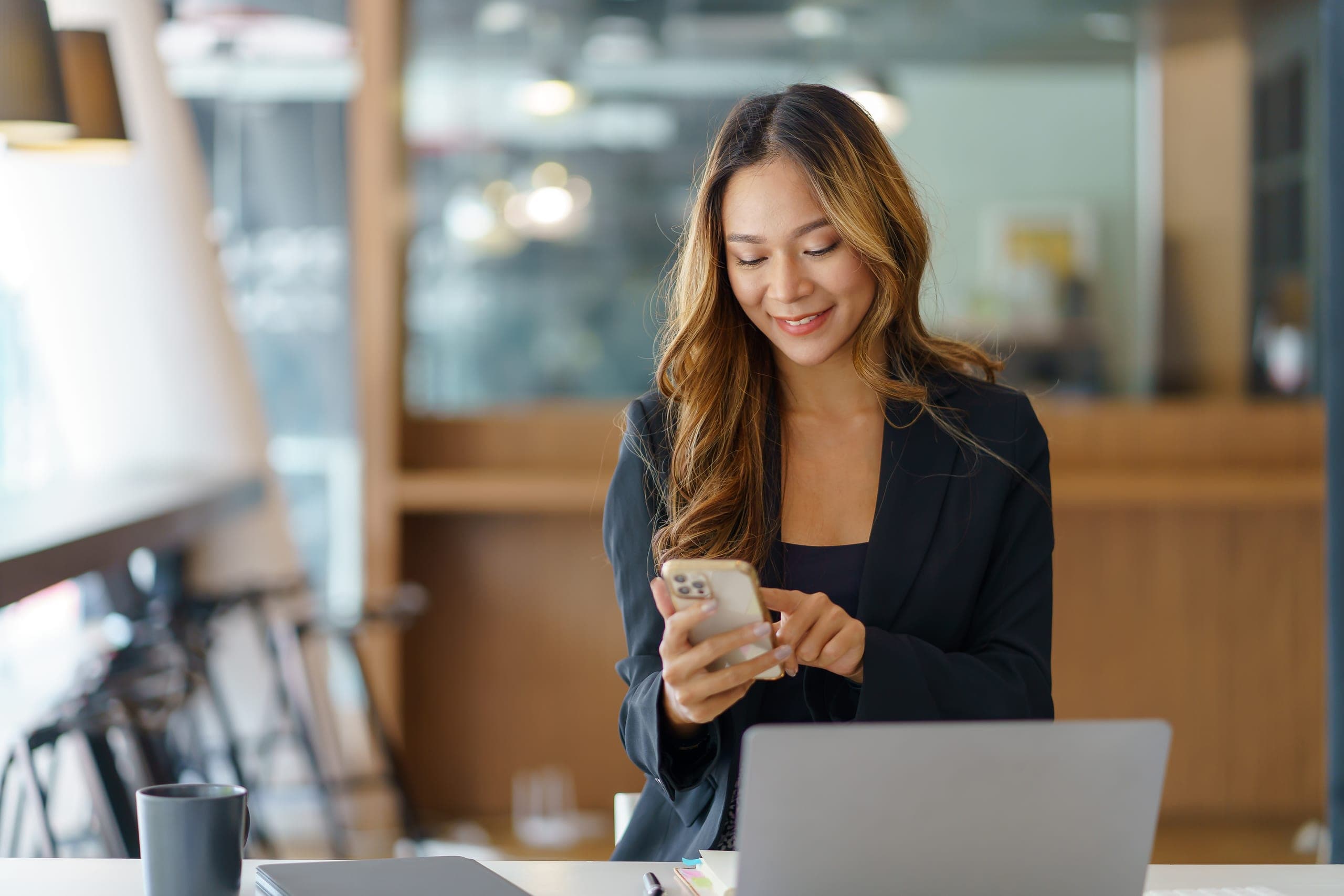 Woman smiling at her phone at an office counter