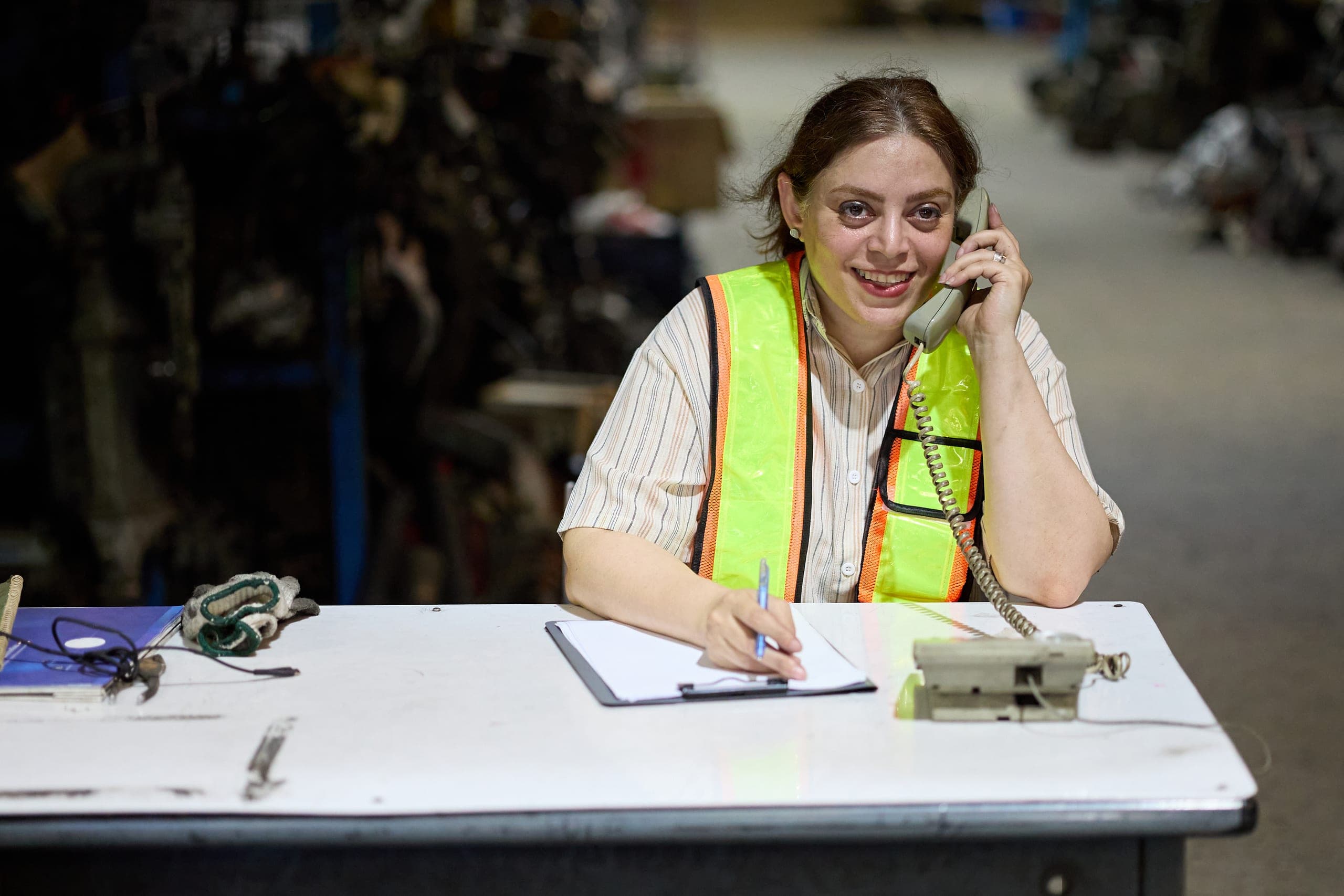 Office worker in a safety vest on the phone, taking notes